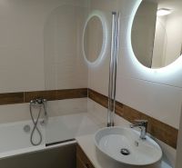 A bathroom with a bathtub, sink, and mirror in a 2-room apartment.