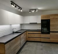 Modern kitchen in a 2-room apartment with white tiles and wood decor.