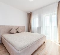 A bright bedroom with a large bed and a wooden decor floor in a 2-room apartment.