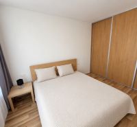 Bedroom in a two-room apartment with a bed, nightstand, and wardrobe with a wooden decor.