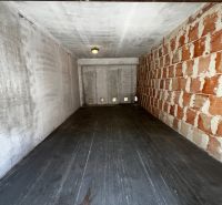 An empty garage with a wood-patterned floor and a brick wall in Dúbravka on Hanulova.
