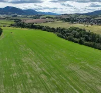 Agricultural and forest lands around Žilina with green fields and forests on the horizon.