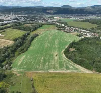 Aerial view of agricultural and forest land around Žilina, surrounded by a village.