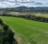 Extensive agricultural and forest lands around Žilina, with views of the hills and the village.