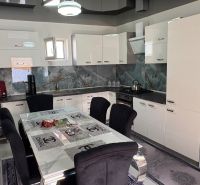 A kitchen in a family house with white cabinets, a dining table, and appliances.