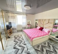 A bedroom in a family house with a mirrored wardrobe, patterned carpets, and a decorative ceiling.