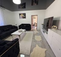 Living room of a family house with dark sofas, white furniture, and decorations.