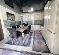 The kitchen of a family house with a dining table, dark chairs, and decorative tiling.