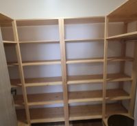 A wardrobe in a 2-room apartment with wooden shelves for storing clothes.