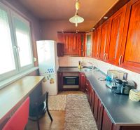 A kitchen with appliances and wooden decor in a 3-room apartment.