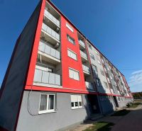 Apartment building in Bajč on Bajč Street with red elements and balconies.