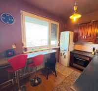 A kitchen in a 3-room apartment with bar stools and a wooden decor floor.