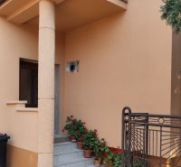 A family house in Krušovce with a terrace, railing, flowers, and a dog in the yard.