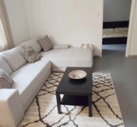 Living room in a two-room apartment with a sofa and a television on a dark table.