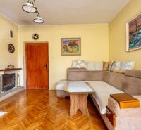 Living room in a family house, wooden decor flooring, fireplace, sofa, paintings on the walls.