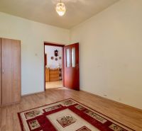 A room in a family house with a wooden decor floor, a carpet, and a wardrobe.