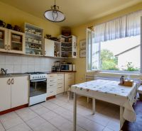 A kitchen in a family house with white cabinets, a stove, and a large window.
