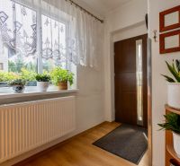 Entrance hallway of a family house with wood-patterned flooring, flower pots, and decorations.