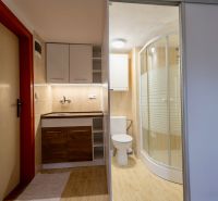 A bathroom in a family house with a bathtub, a sink, and a floor with a wooden decor.