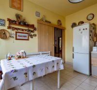 A kitchen in a family house with an embroidered tablecloth, a refrigerator, and decorations on the wall.