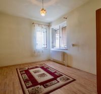 A room in a family house with a wooden decor floor and a carpet on the edge.
