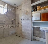 A bathroom with an open shower and a sink in a family house.