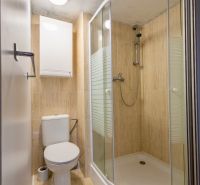 A bathroom in a family house with a toilet and a shower, light tiles.