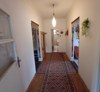 A hallway in a family house with a wooden decor floor and a carpet.