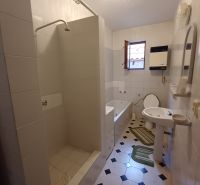 White bathroom with a bathtub, shower, and toilet in a family house.