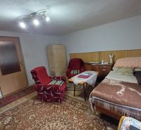 Living room in a family house with an armchair, carpet, and bed.