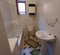 A family house bathroom with a bathtub, sink, and toilet, light tiles.