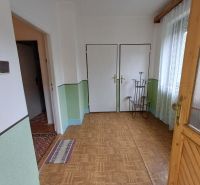 Entrance hallway in a family house with a wooden decor floor, light walls, and curtains.