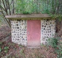 A stone cellar in a family house in Drnava surrounded by dense forest vegetation.