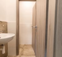 A bathroom in an office with a sink, mirror, and tiles with a wood decor.