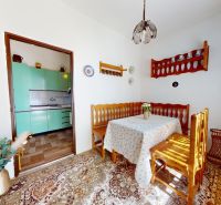 Dining room in a family house with a sofa, table, and view into the kitchen with turquoise cabinets.