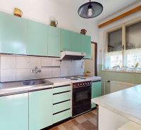 A kitchen with retro cabinets in a family house, with a dining counter under the window.