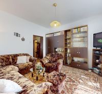 Living room with a floral carpet, sofa, television, and wooden furniture in a family house.