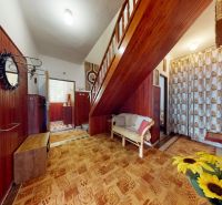 Interior of a family house with wooden decor, flowers, and a staircase.