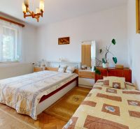 A bedroom in a family house with a double bed, a single bed, and a floor with a wooden decor.