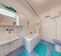 A bathroom in a family house with a bathtub and white tiles.