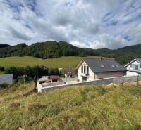 Residential plots in Považská Bystrica with a view of green hills and houses.