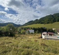 Residential plots in Považská Bystrica with hills and houses in the background.