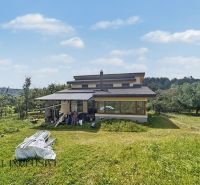 A family house in Veličná with an extensive lawn and surrounding trees.