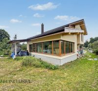 A family house in Veličná with a spacious garden surrounded by greenery and a blue sky.