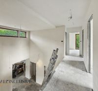 A spacious hallway in a family house with a view of the garden, white walls, and a ladder.