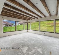 Interior of a family house with large windows and wooden beams on the ceiling.