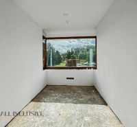 A view from a family house through a large window of the mountains and greenery.