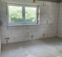 Interior of a family house with a large window, concrete floor, brick walls.