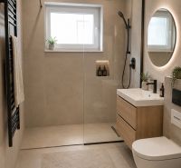 A bathroom in a family house with a shower, a mirror, and light brown tiles.
