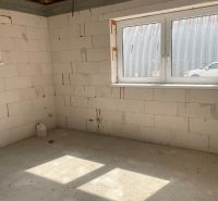A room construction in a family house with an open wooden ceiling and a concrete floor.